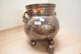 A brown glazed pottery vase decorated with geometrical patterns, two handles and raised on ball