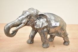 An elephant sculpture with tusks and trunk raised up in a feeding position, h18.5cm