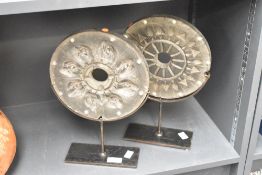 A pair of circular rubber sculptures raised on a black metal stand, h34cm