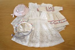 Three early to mid-20th century doll's dresses. Two cream cotton examples with delicate lace detail,