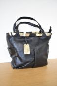 A vintage tote handbag in black leather with gold pleather details and gold metal hardware, labelled