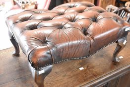 A reproduction buttoned leather footstool