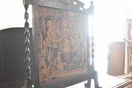 An early 20th Century oak firescreen having barley twist supports and fabric insert