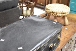 A vintage suitcase and seagrass three legged stool