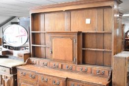 A period oak dresser of breakfront design , having open delft rack with central cupboard , over