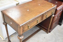 An early 20th Century oak side table having two frieze drawers, on turned legs and H frame, width