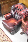 A reproduction red leather swivel captains style office chair and a similar oxblood button back easy