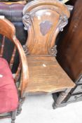 A Victorian oak hall chair having cartouche to back and turned legs