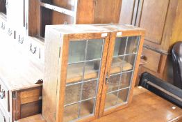 An early 20th Century oak cabinet top of small proportions having leaded glass doors, width