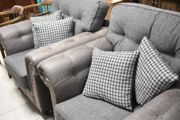 A pair of modern grey chesterfield style armchairs, and complimentary loose cushions