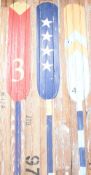 A decorative hand-painted rustic planked pine panel, decorated with three colourful oars, signed J