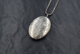 A silver locket of oval form having engraved scroll decoration on a 23' box chain, approx 25.7g