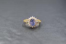 An 18ct gold sapphire and diamond set cluster ring, the central oval cut sapphire measuring