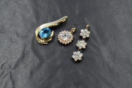 A yellow metal pendant stamped 14K having an oval blue topaz stone in a claw set moulded swirl