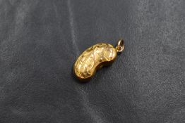 A 9ct gold lucky bean charm having scroll engraving to one side, marked 9ct, 1.2g