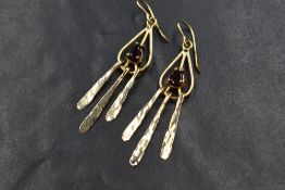 A pair of 14ct gold garnet set drop earrings, the pear cut garnets in openwork settings with three