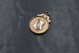 A 9ct rose gold medallion, having a vacant shield and personalised engraving to the reverse,