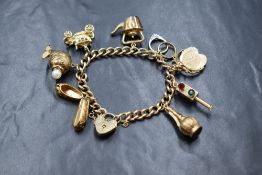 A 9ct gold curb link charm bracelet, marked 375, having a 9ct gold heart padlock marked 375, and