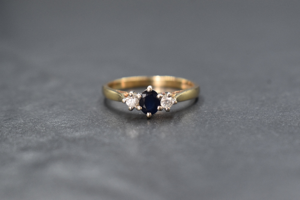 A 9ct gold sapphire and diamond trilogy ring having a central oval sapphire, approx 0.25ct,