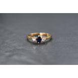 A 9ct gold sapphire and diamond trilogy ring having a central oval sapphire, approx 0.25ct,