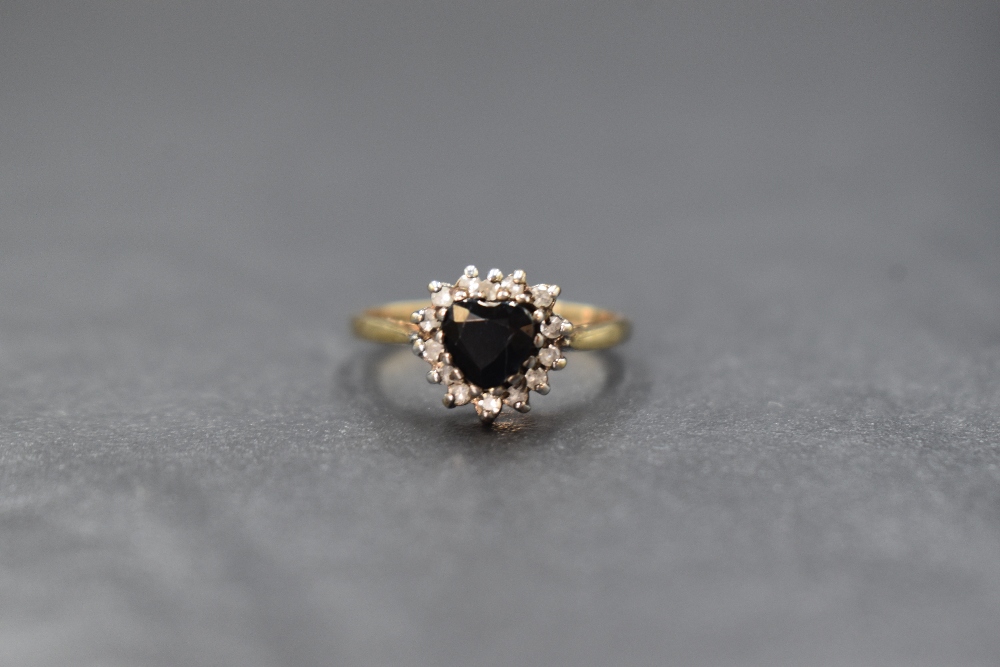 A 9ct gold sapphire and diamond set cluster ring, the central heart cut sapphire in a fourteen