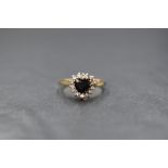 A 9ct gold sapphire and diamond set cluster ring, the central heart cut sapphire in a fourteen