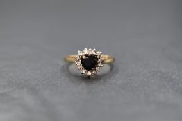 A 9ct gold sapphire and diamond set cluster ring, the central heart cut sapphire in a fourteen