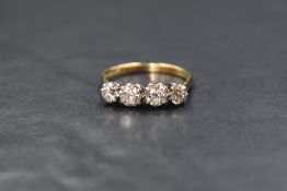 An 18ct gold diamond set four stone ring, the two central brilliant round cut diamonds measuring