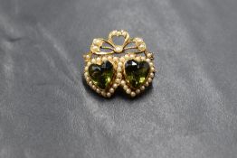 A yellow metal presumed gold seed pearl and green paste set double heart brooch, the twinned heart