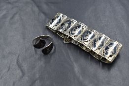 A Siamese silver articulated panel bracelet with black enamel engraved figured panels and