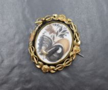 A large yellow metal mourning hair brooch, the central panel having decorative hair scrolls in an