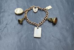 A 9ct rose gold curb link bracelet having a padlock clasp and five (not gold) charms including a