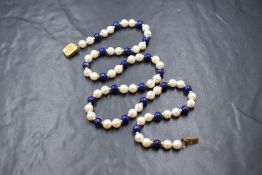 A string of cultured pearls and lapis lazuli beads, the pearls of even form having a white lustre,