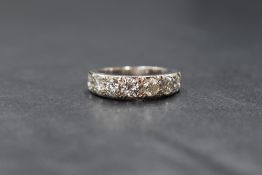 A white metal, presumed 18ct white gold, seven stone diamond half eternity ring, each brilliant