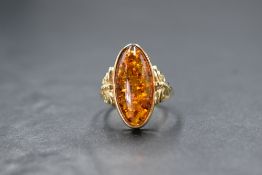 A 9ct gold Baltic amber ring having an oval amber cabochon in a collared mount with moulded