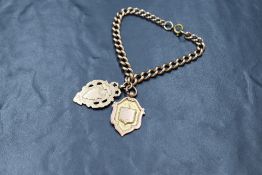 A 9ct rose gold curb link bracelet with two 9ct rose gold shield medalions, one being vacant, approx