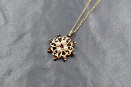 A 9ct gold seed pearl and garnet pendant having pierced heart wreath decoration with an 18' 9ct gold