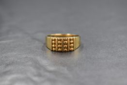 A 9ct gold signet style ring, having a raised panel with alternating bands and bead decoration,