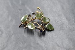 A yellow metal vine motif brooch, the carved green hardstone in leaf motifs, interspersed with