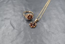 A 9ct gold garnet set cluster ring, the central round cut garnet in a six round cut garnet surround,