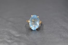 A 9ct gold blue topaz ring having a large oval stone in a six claw raised mount with moulded