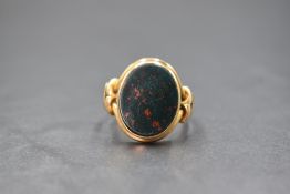 A yellow metal presumed gold bloodstone set signet ring, the oval bezel set bloodstone panel in a