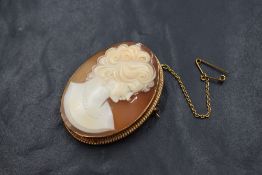 A 9ct gold cameo set brooch, the cameo depicting a maiden in profile in a bezel setting with rope