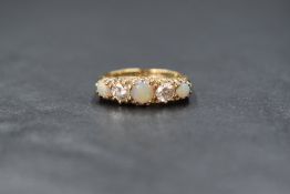 A 9ct gold, opal and cubic zirconia ring having three graduated opal cabochons interspersed by two