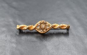 A yellow metal presumed gold diamond set bar brooch, the nine diamond cluster mounted in a twisted