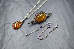 A silver amber set brooch, the amber oval cabochon in a bezel setting with branch and leaf