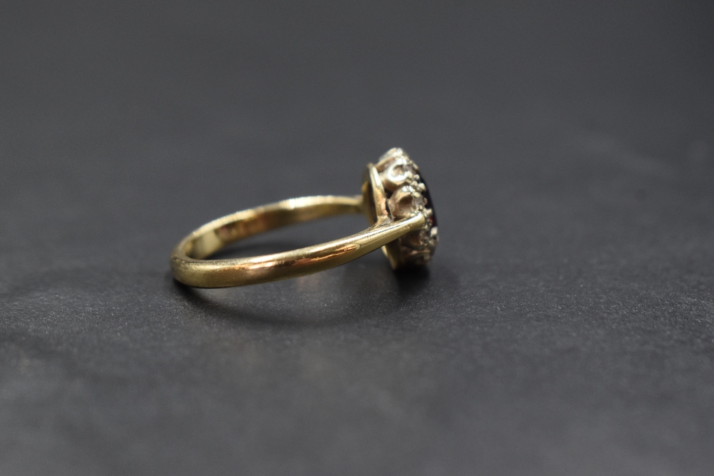 A 9ct gold garnet and white gemstone set cluster ring, the central oval cut garnet in a ten white - Image 2 of 3