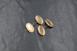 A pair of 9ct gold cufflinks, the oval panels having decorative engraved borders with chain links,