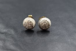A pair of white metal diamond set stud earrings, the round cut pave set diamonds in a textured