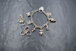 A silver charm bracelet having a padlock clasp and seven charms including football boots and